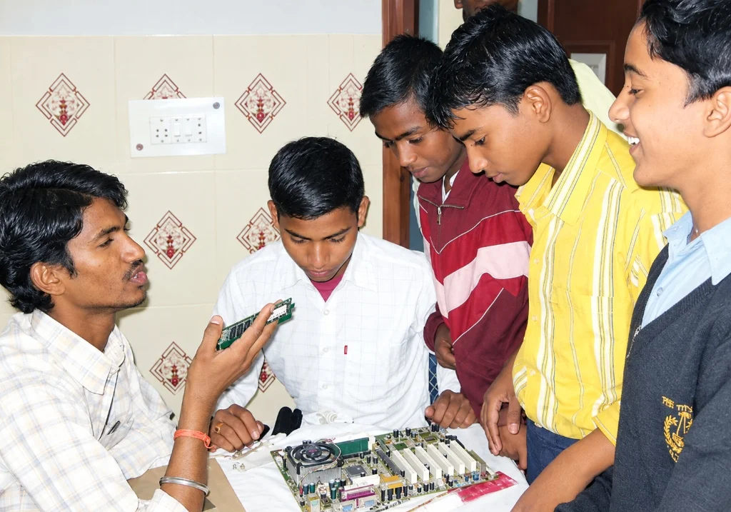 Instructor demonstrating computer hardware and electronic components to students